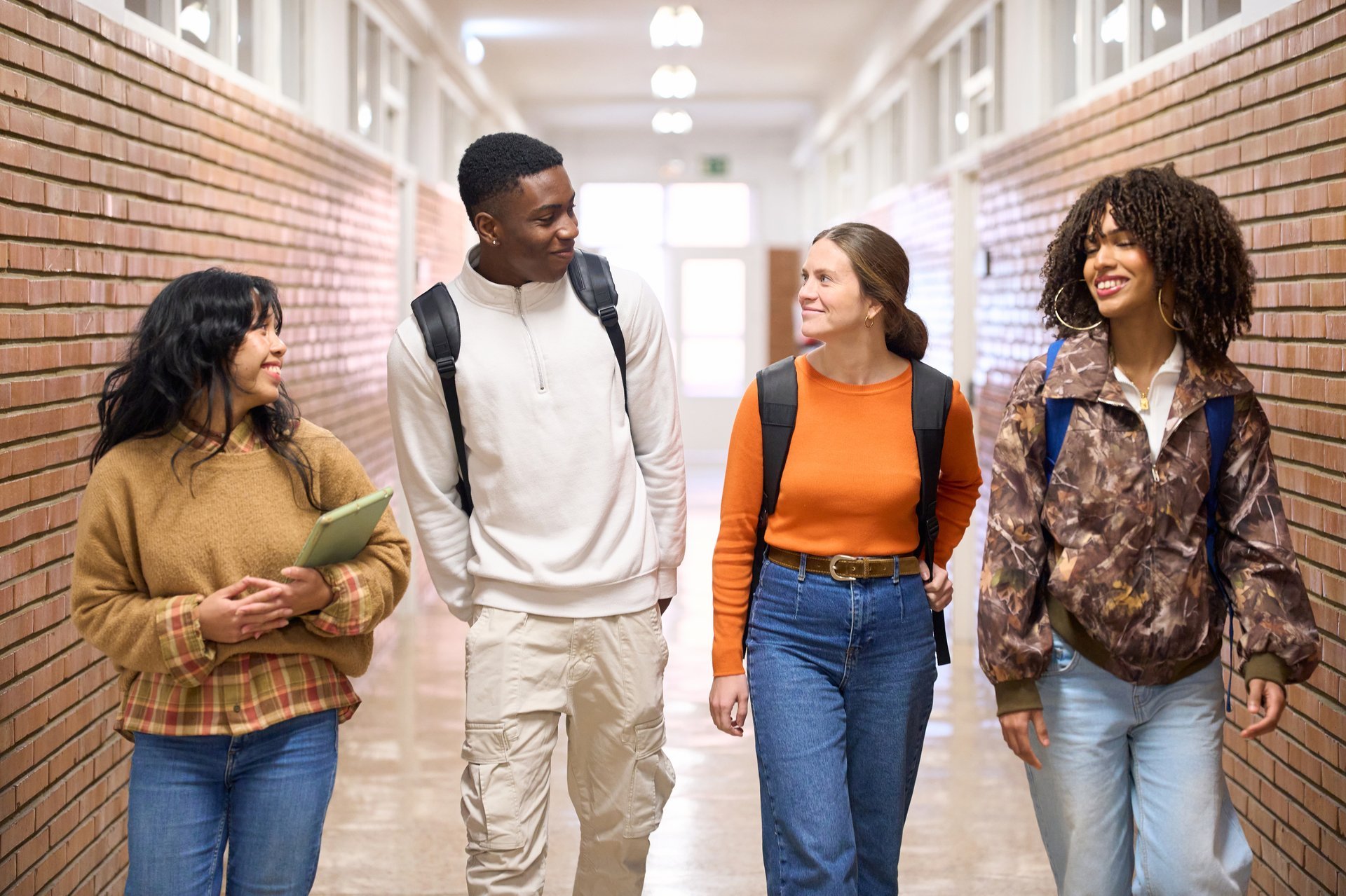 Diverse high school students walking through a bright school hallway together