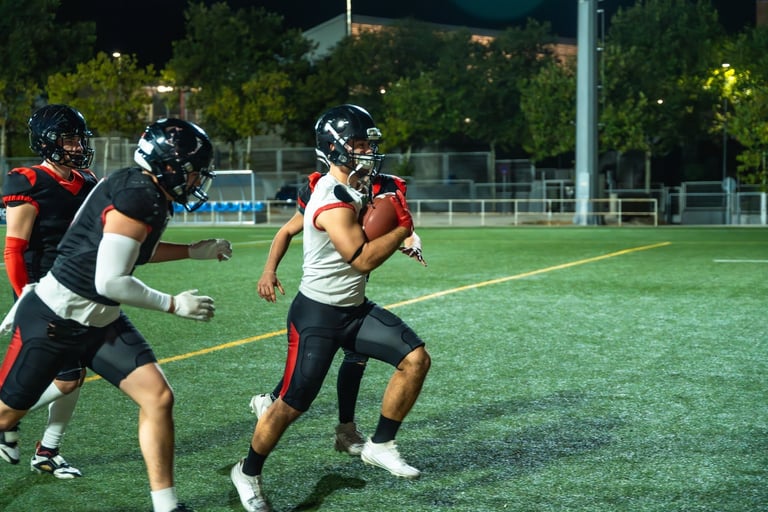 Young players competing under stadium lights during a night American football game
