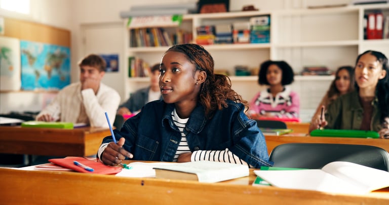 Teenage girl listening with attention in a high school classroom, writing notes