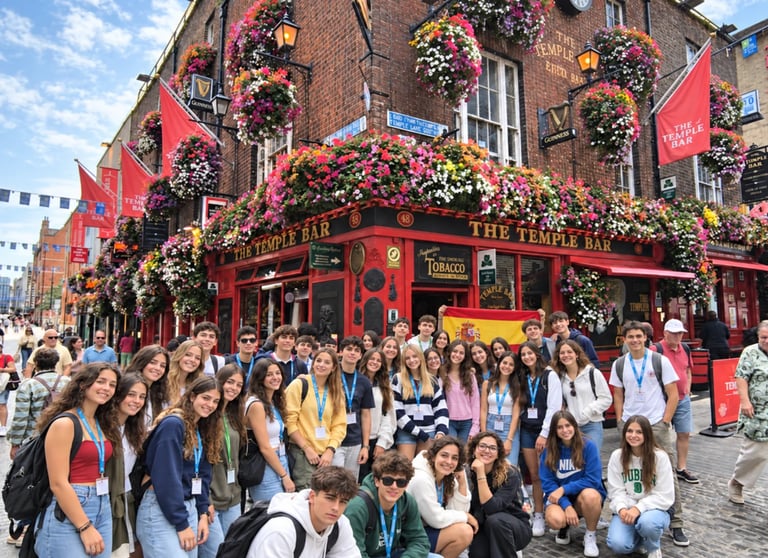 Large group of tourists posing in front of The Temple Bar, a red historic pub in Dublin decorated with colorful hanging flowers