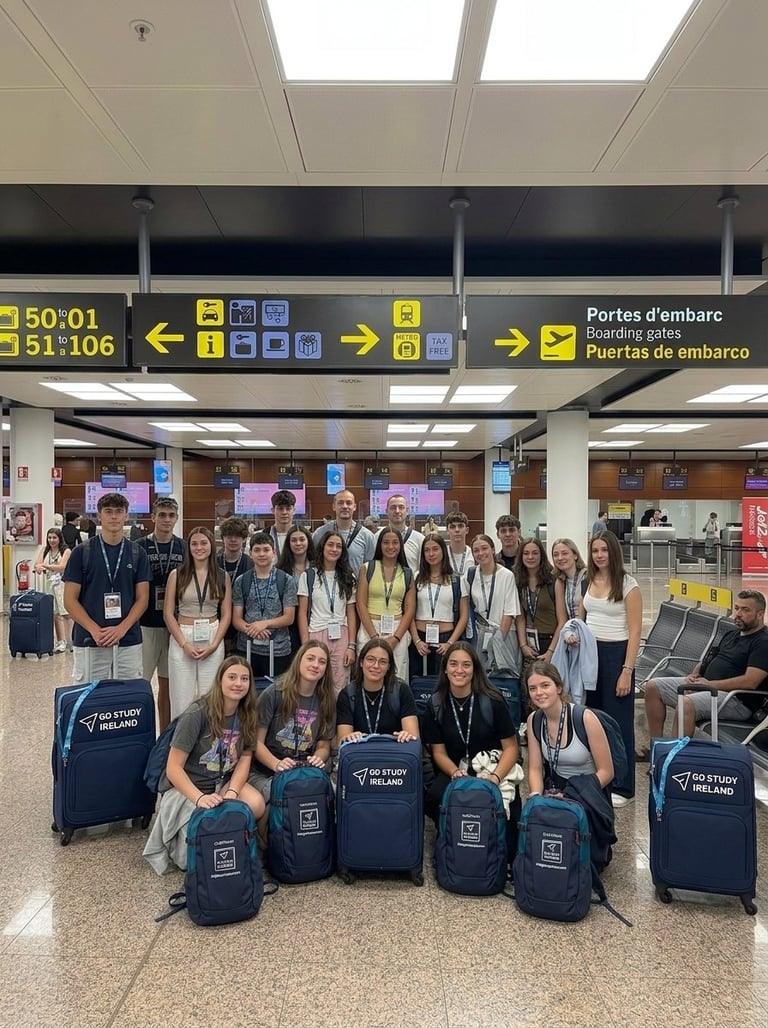 Large group of people wearing lanyards posing with luggage in an airport terminal under departure signs