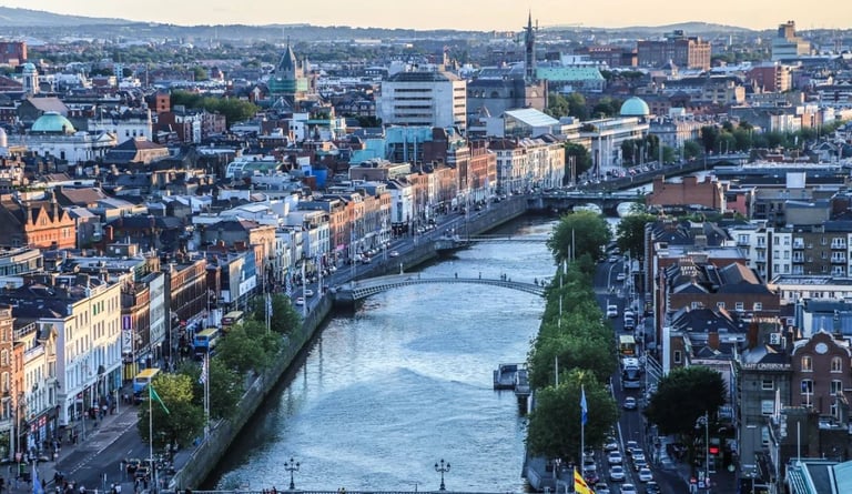 Aerial view of a European city with a river running through it, historic buildings, and church spires visible across the urban landscape
